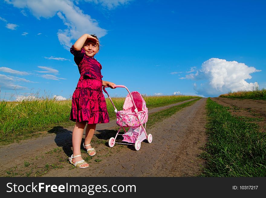 The little girl on a farmer field with carriage. The little girl on a farmer field with carriage