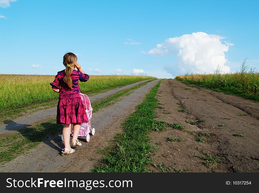 The little girl on a farmer field with carriage. The little girl on a farmer field with carriage