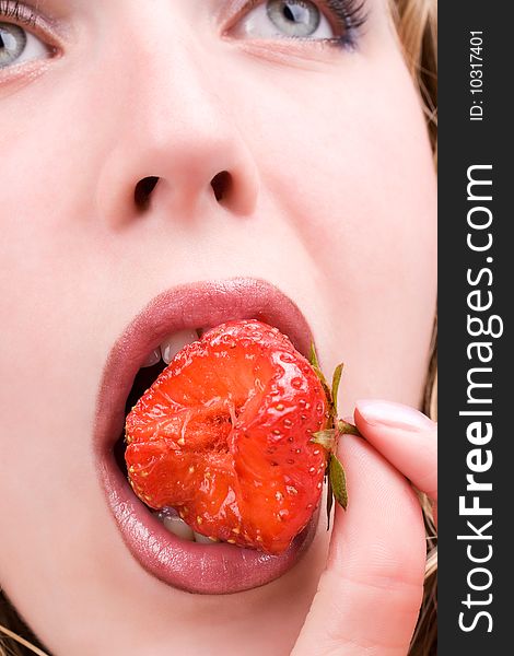 Pretty female model eating tasty strawberry