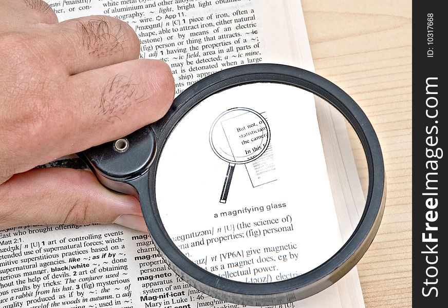 Attentive reader reading dictionary with magnifier glass