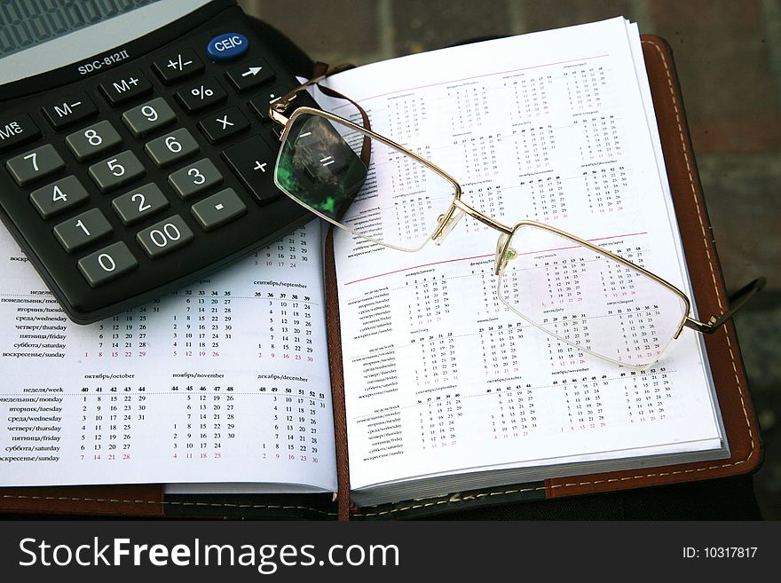 Business still-life with glasses, calculator and organizer
