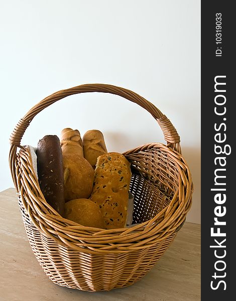 Basket with the bread, containing two white bread, two baguets, black bread with caraway seeds and a roll with raisin. Basket with the bread, containing two white bread, two baguets, black bread with caraway seeds and a roll with raisin