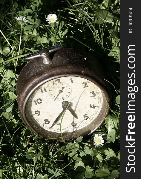 Old metal alarm clock in the grass