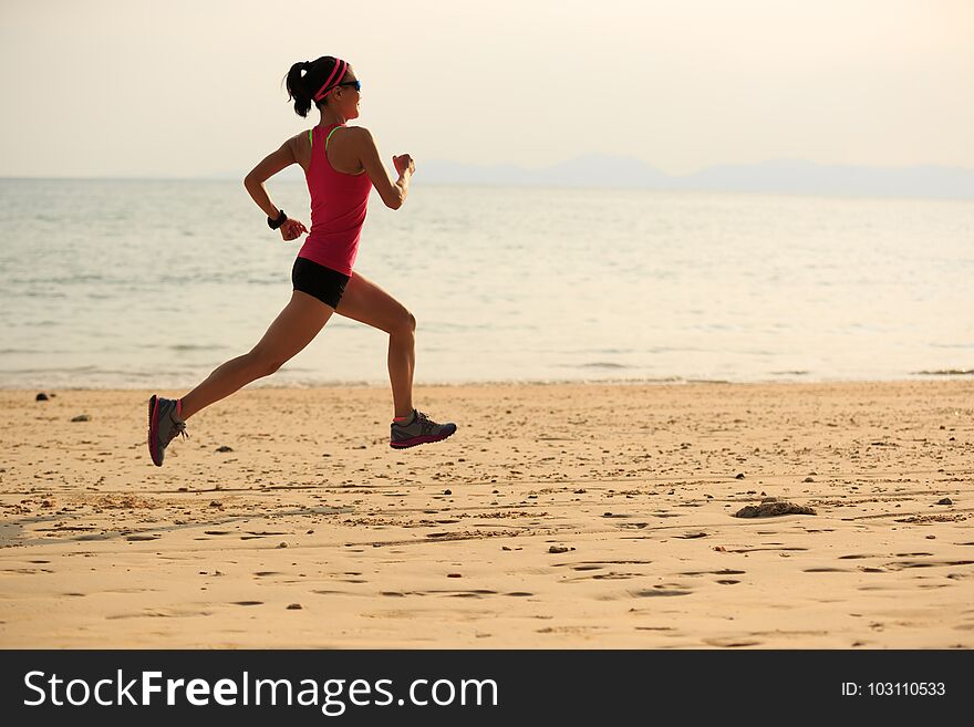 Sporty woman runner running on seaside sandy beach