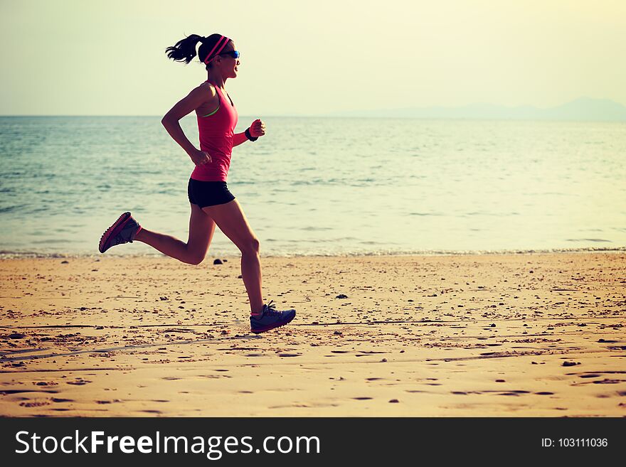 Sporty woman runner running on seaside sandy beach