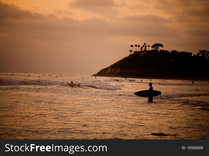 A surfer heads our at sunset for a surf session. A surfer heads our at sunset for a surf session.