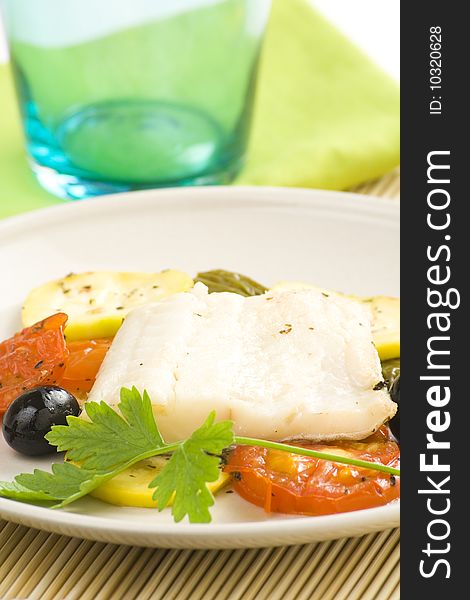 Fillet of cod baked tomatoes zucchini black olives isolated