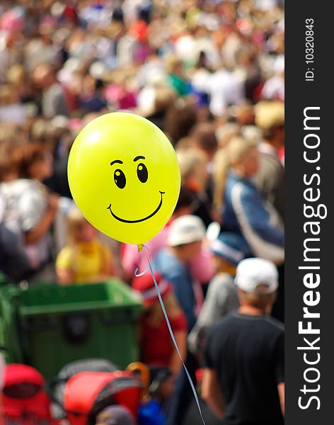 Happy looking and smiling yellow air balloon with blurry people on background. Happy looking and smiling yellow air balloon with blurry people on background.