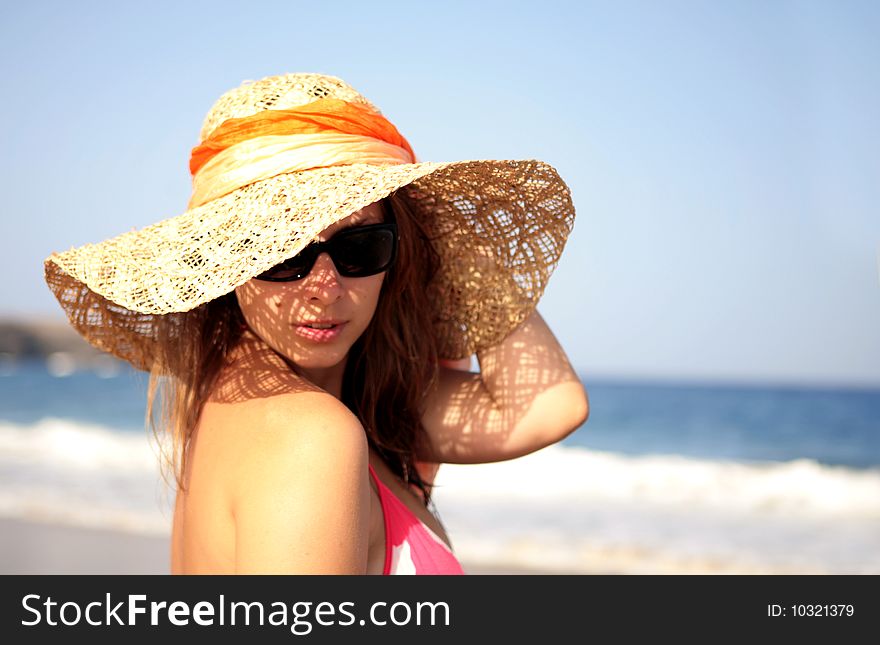 Beautiful woman standing by the sea in a  hat. Beautiful woman standing by the sea in a  hat