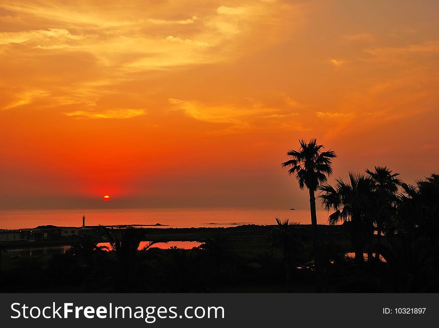 Serene tropical sunset with sun setting into the ocean water