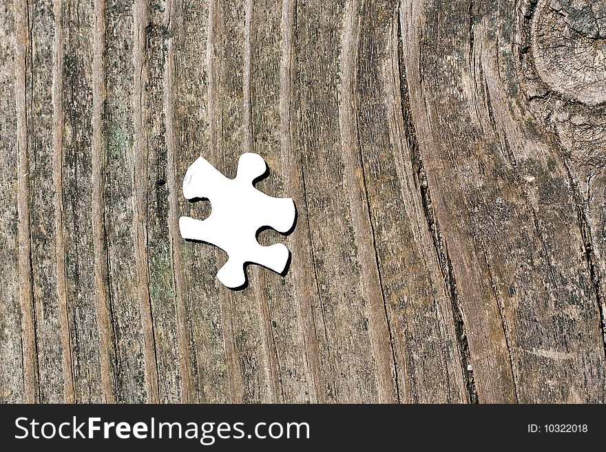 A single puzzle piece shot on a wooden background. A single puzzle piece shot on a wooden background