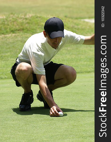 Man on golf course setting ball ready to putt. Man on golf course setting ball ready to putt