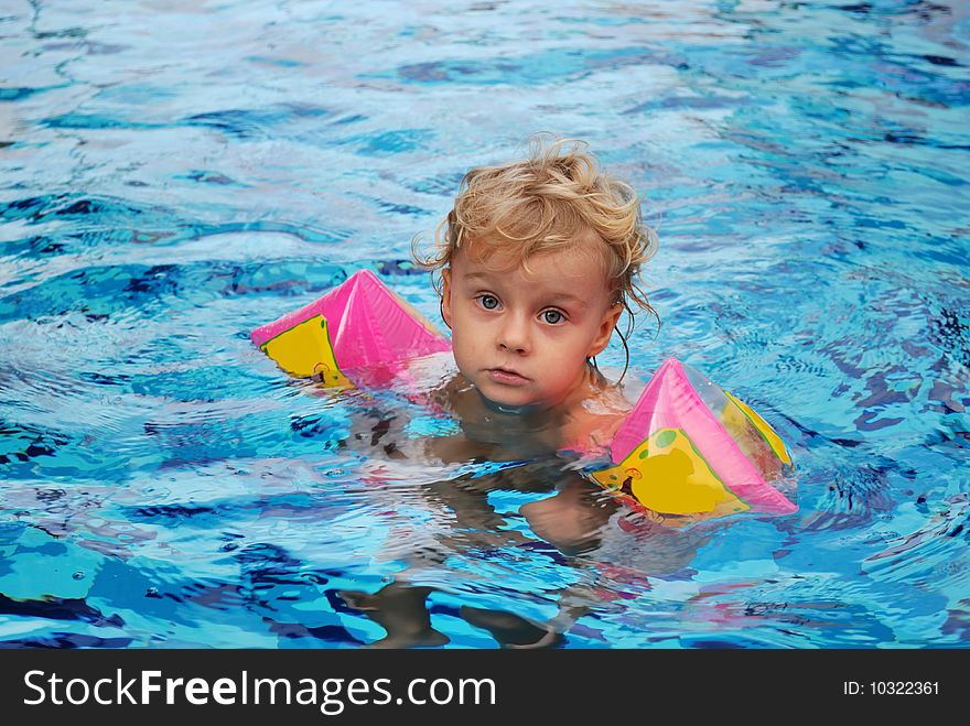 Little girl with inflatable oversleeves floats in pool. Little girl with inflatable oversleeves floats in pool