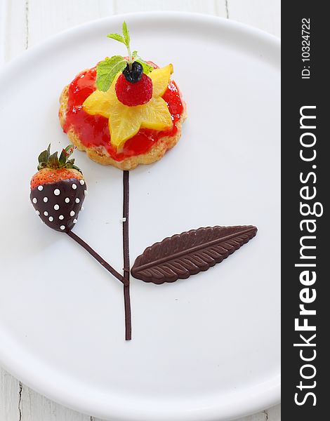 Fruit tart with fresh fruit like starfruit,  styling with chocolate coated strawberry, like a flower tree.