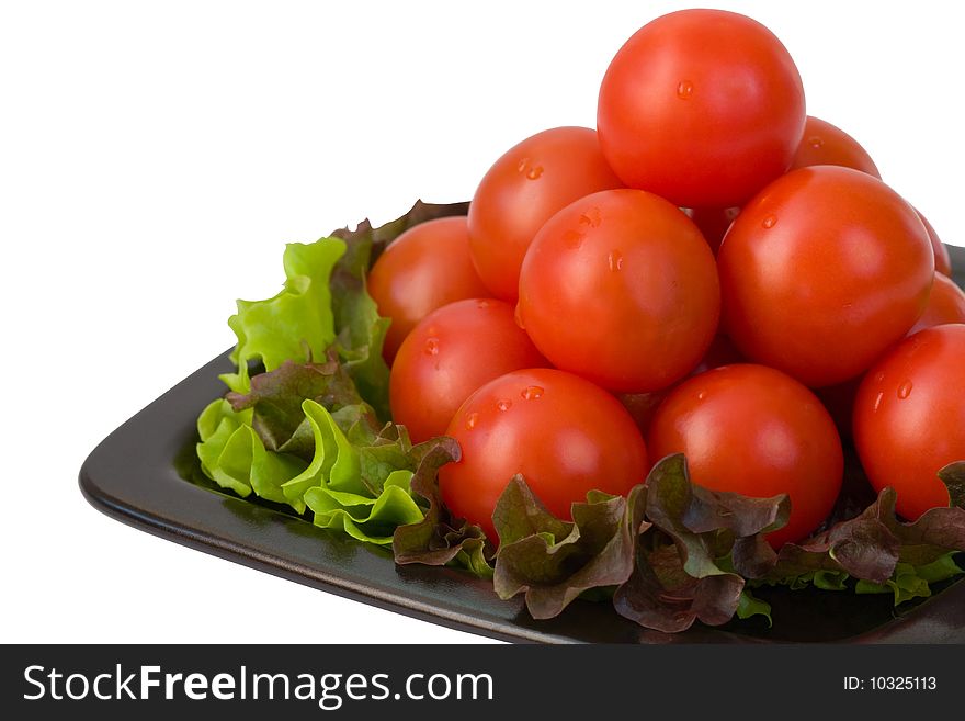 Small tomatoes are combined in a pyramid on a black plate and leaves of salad. Small tomatoes are combined in a pyramid on a black plate and leaves of salad.
