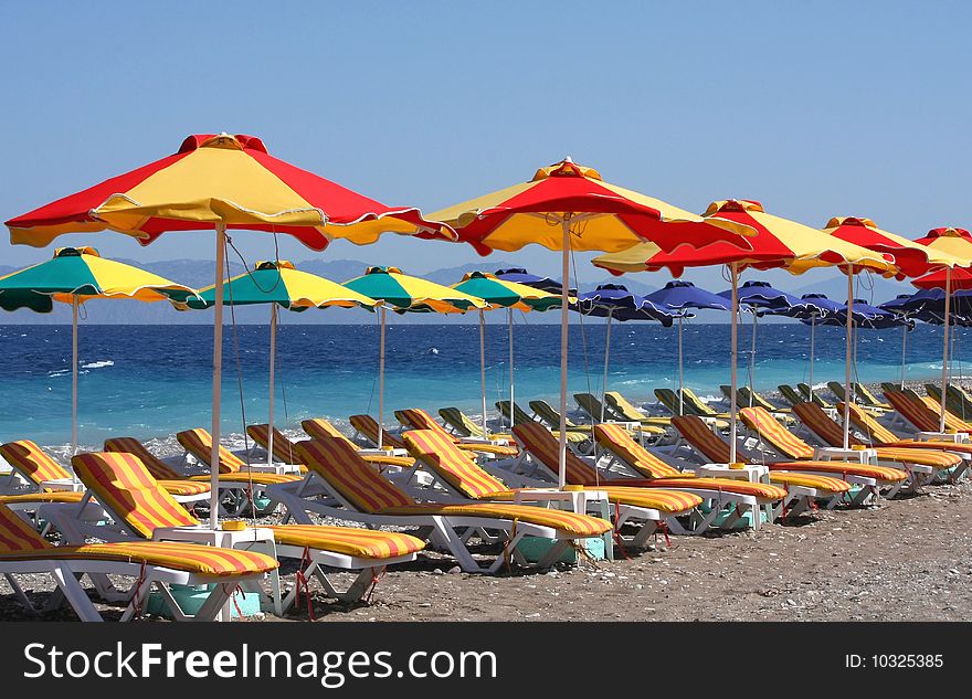 Beach with sun loungers and umbrellas near the blue sea. Beach with sun loungers and umbrellas near the blue sea