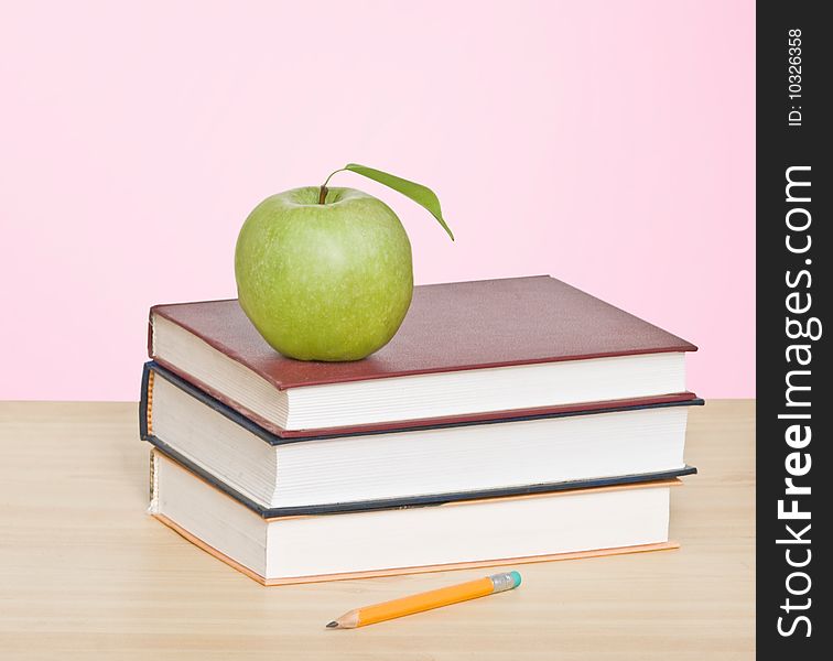 Red apple and pencil on top of books