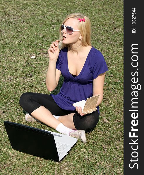 Studying girl with a laptop sitting on grass