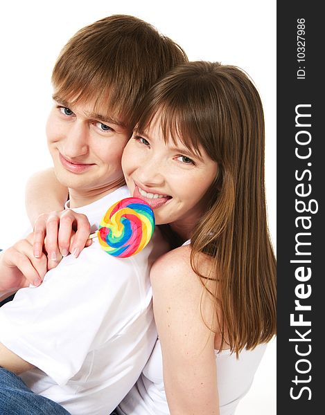 A young teenage couple shares a lollipop