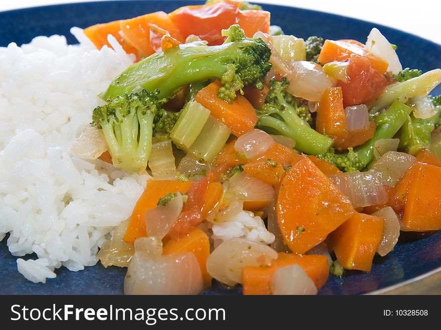 Stir-fried vegetables, carrot, broccoli, celery, onion and tomato, and rice on a blue plate. Stir-fried vegetables, carrot, broccoli, celery, onion and tomato, and rice on a blue plate.