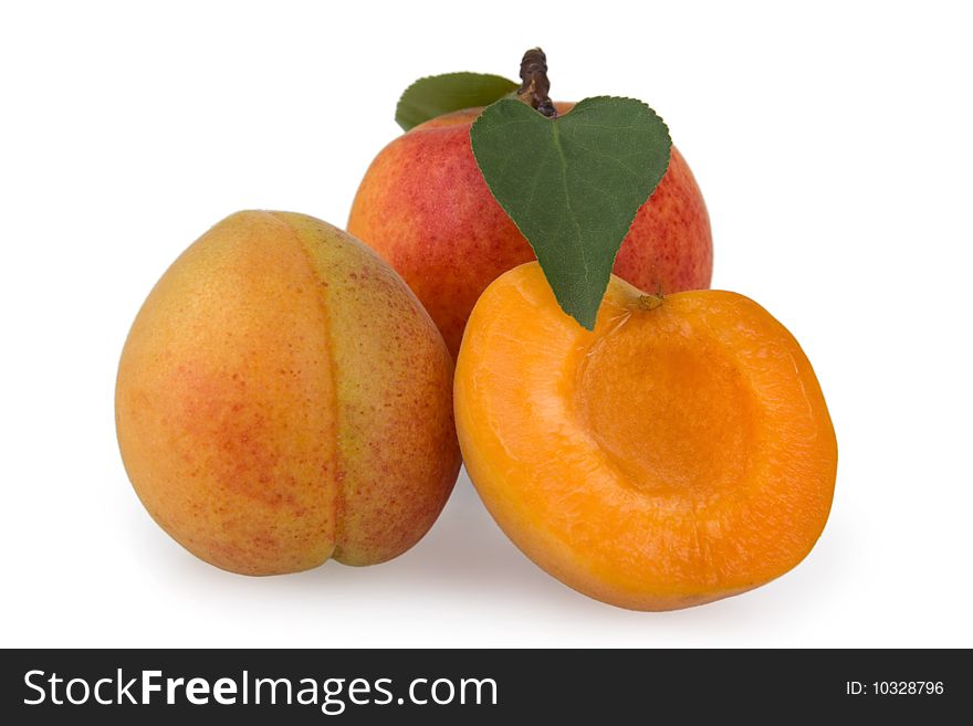 Ripe apricots with leaves on white background.