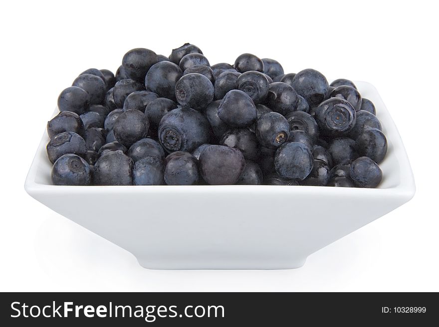 Ripe bilberries in saucer on white background.