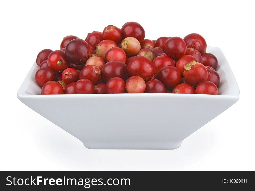 Ripe cranberries in saucer on white background.