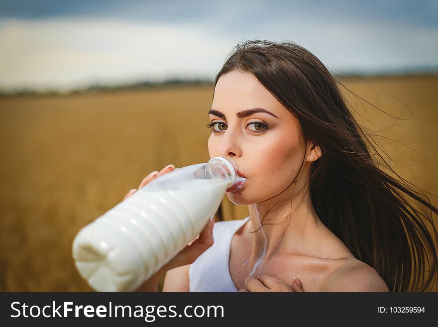 Beautiful woman drinking milk in countryside field looking at camera. close-up to very beautiful girl with amazing green eyes and attractive face. Beautiful woman drinking milk in countryside field looking at camera. close-up to very beautiful girl with amazing green eyes and attractive face
