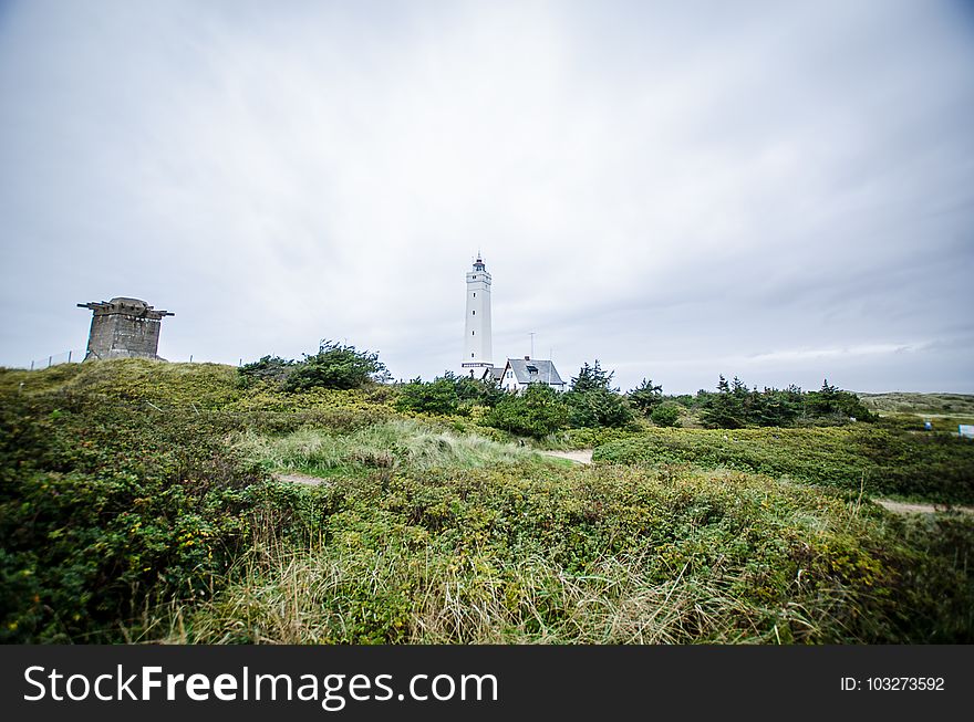 White Lighthouse In The Background Of Green Fields