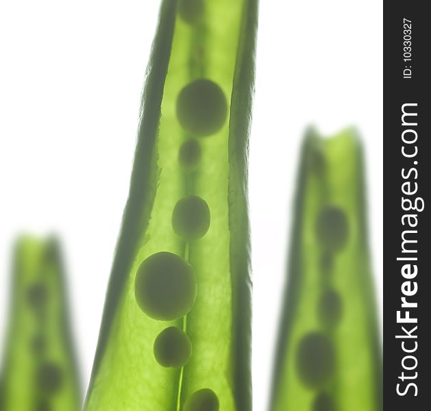 Three pea pods on reflective white background