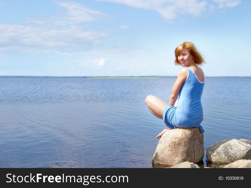 Beautiful young woman on the shore stone