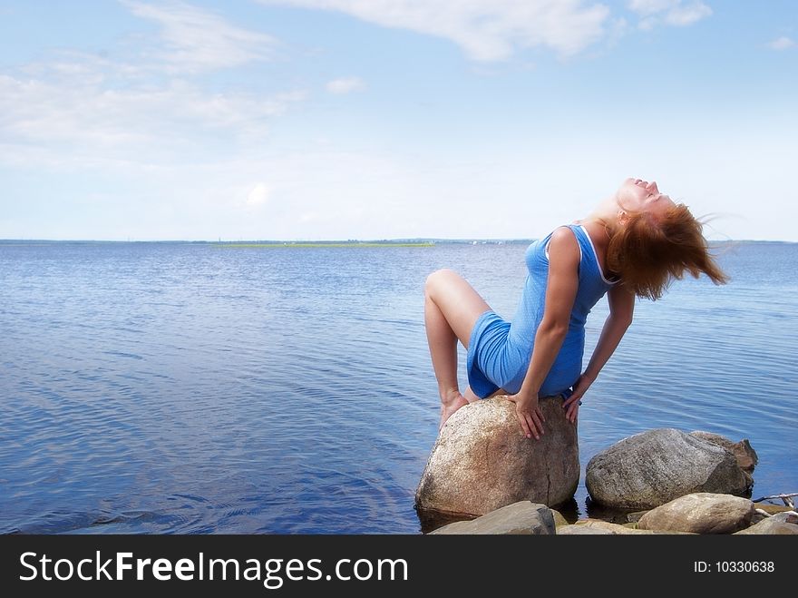 Beautiful young woman sitting on the shore stone. Beautiful young woman sitting on the shore stone