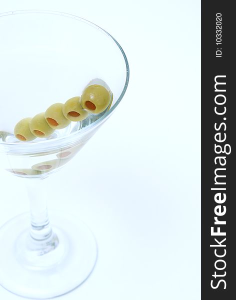 A macro shot of a martini with extra olives.