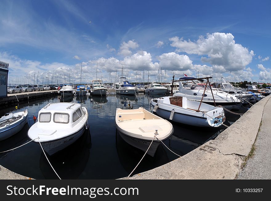 Yachts in marina with cloudy sky