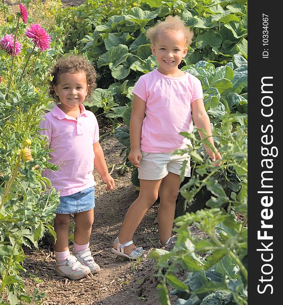 Two beautiful ethnic sisters Little girls in the garden are wearing pink shirts and have adorable smiles.