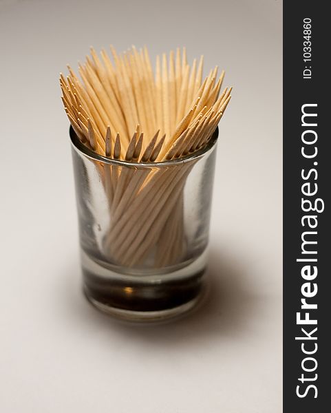 Isolated toothpicks in a small glass on white background, close-up. Isolated toothpicks in a small glass on white background, close-up