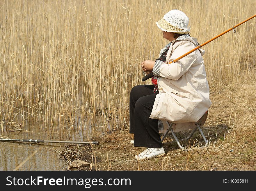 The woman fishes at coast of lake in reeds. The woman fishes at coast of lake in reeds