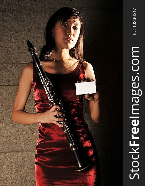 Beautiful young Asian woman in red dress holding a musical instrument  and name card in an underground tunnel. Beautiful young Asian woman in red dress holding a musical instrument  and name card in an underground tunnel
