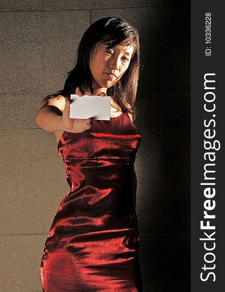 Beautiful young Asian woman in red dress showing name card in an underground tunnel. Beautiful young Asian woman in red dress showing name card in an underground tunnel