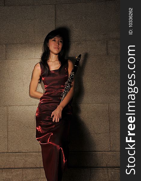 Beautiful young Asian woman in red dress holding a musical instrument in an underground tunnel. Beautiful young Asian woman in red dress holding a musical instrument in an underground tunnel.