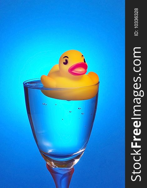 Rubber ducky floating in a glass of water.