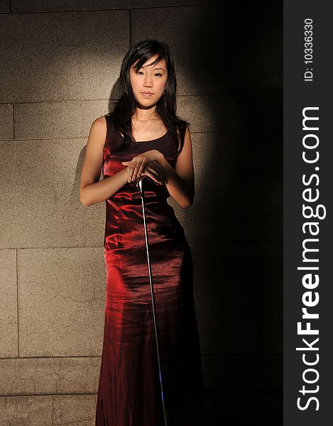 Beautiful young Asian woman in red dress holding a golf stick in an underground tunnel. Beautiful young Asian woman in red dress holding a golf stick in an underground tunnel.