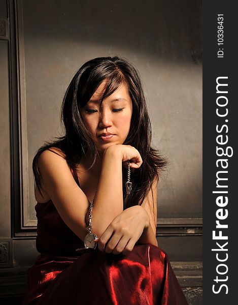 Beautiful young Asian woman in red dress sit and thinking. Beautiful young Asian woman in red dress sit and thinking.