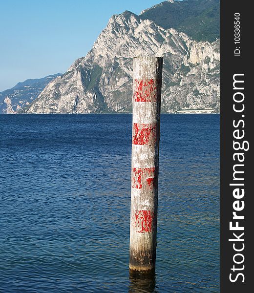 Red and white wooden pole in Lake Garda, Italy