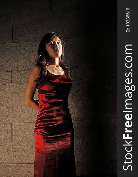 Beautiful young Asian woman in red dress standing or waiting.