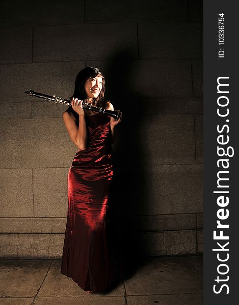 Beautiful young Asian woman in red dress holding a musical instrument. Beautiful young Asian woman in red dress holding a musical instrument.