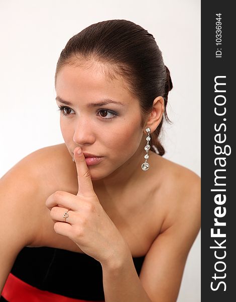 Portrait of young charming girl in an evening dress with finger on lips. Portrait of young charming girl in an evening dress with finger on lips