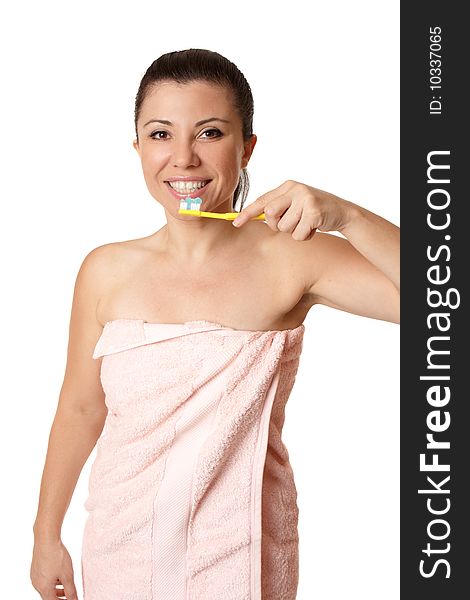 A female wrapped in a pink towel holding a toothbrush with toothpaste and smiling. A female wrapped in a pink towel holding a toothbrush with toothpaste and smiling.
