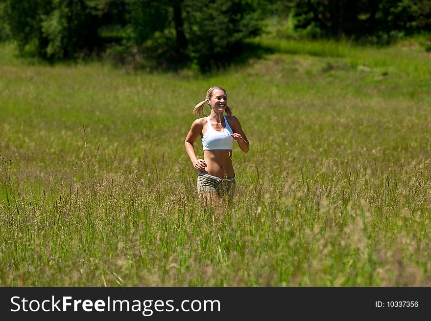 Summer - Young woman jogging in a meadow