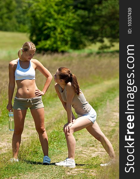 Summer - Two young women exercising in a meadow on sunny day